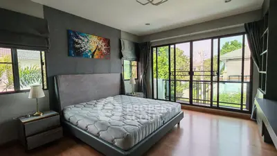 Spacious bedroom with large windows and balcony access, featuring modern decor and natural light.