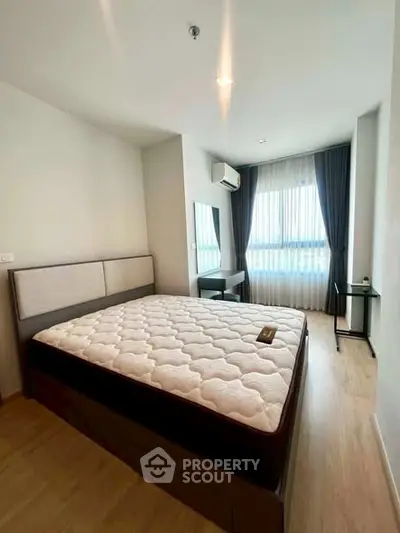 Spacious bedroom with large window and modern furnishings in a stylish apartment.
