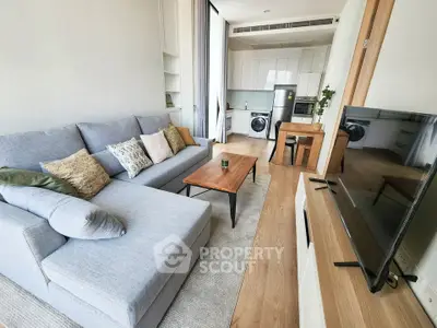 Modern living room with cozy sofa and open kitchen layout in stylish apartment.