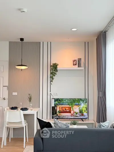 Modern living room with stylish decor and natural light, featuring a cozy sofa and wall-mounted TV.