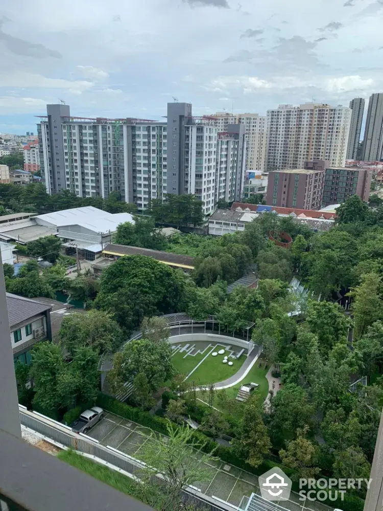 Stunning cityscape view from high-rise apartment overlooking lush green garden and modern buildings.