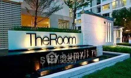 Modern condominium entrance with illuminated signage and landscaped surroundings.