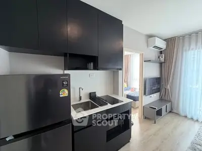 Modern kitchen with sleek black cabinets and integrated appliances in a stylish apartment.
