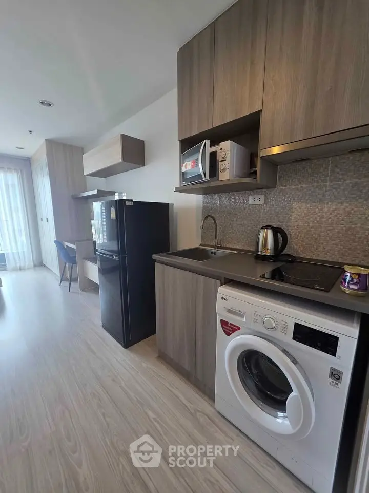Modern kitchen with sleek appliances and wood cabinetry in a stylish apartment.
