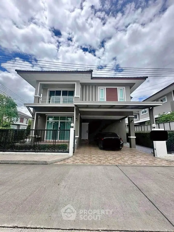 Modern two-story house with carport and spacious driveway in a suburban neighborhood.