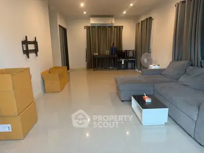 Spacious living room with modern sofa and tiled flooring, ideal for comfortable living.