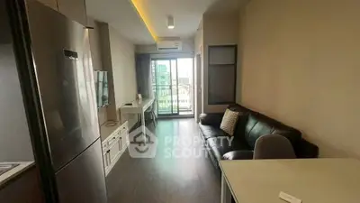 Modern living room with balcony view, sleek furniture, and open layout in urban apartment.