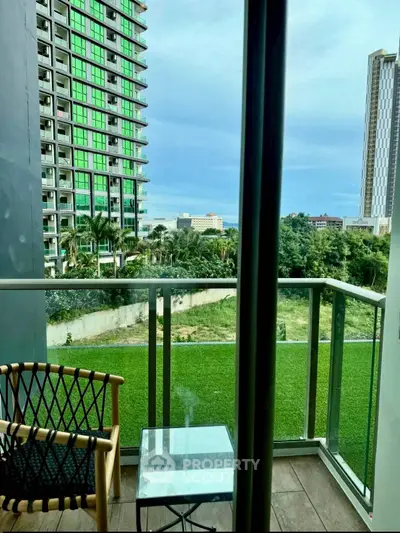 Charming balcony view with lush greenery and modern high-rise buildings, perfect for urban living.