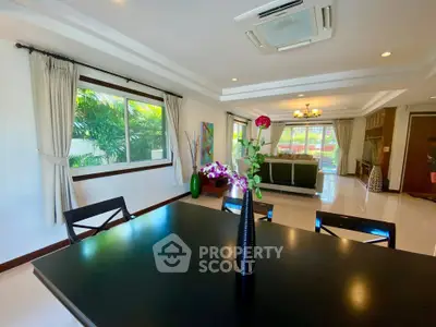 Spacious living room with elegant decor and large windows offering lush garden views.
