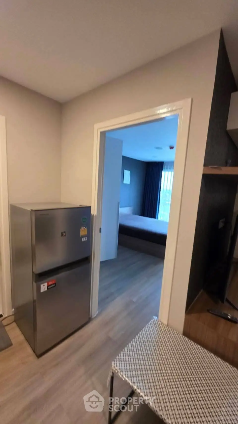 Modern apartment interior with compact kitchen and view into cozy bedroom.