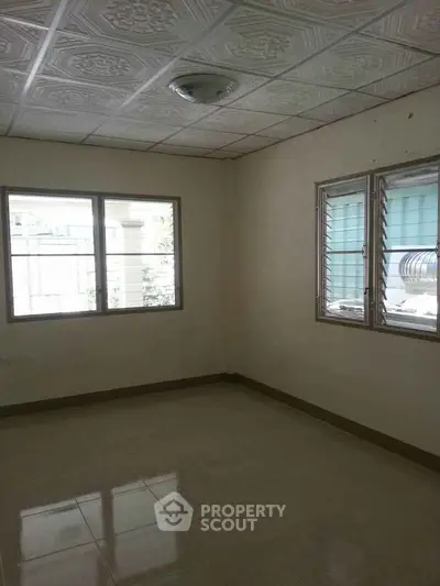 Spacious empty room with tiled floor and large windows, perfect for customization.