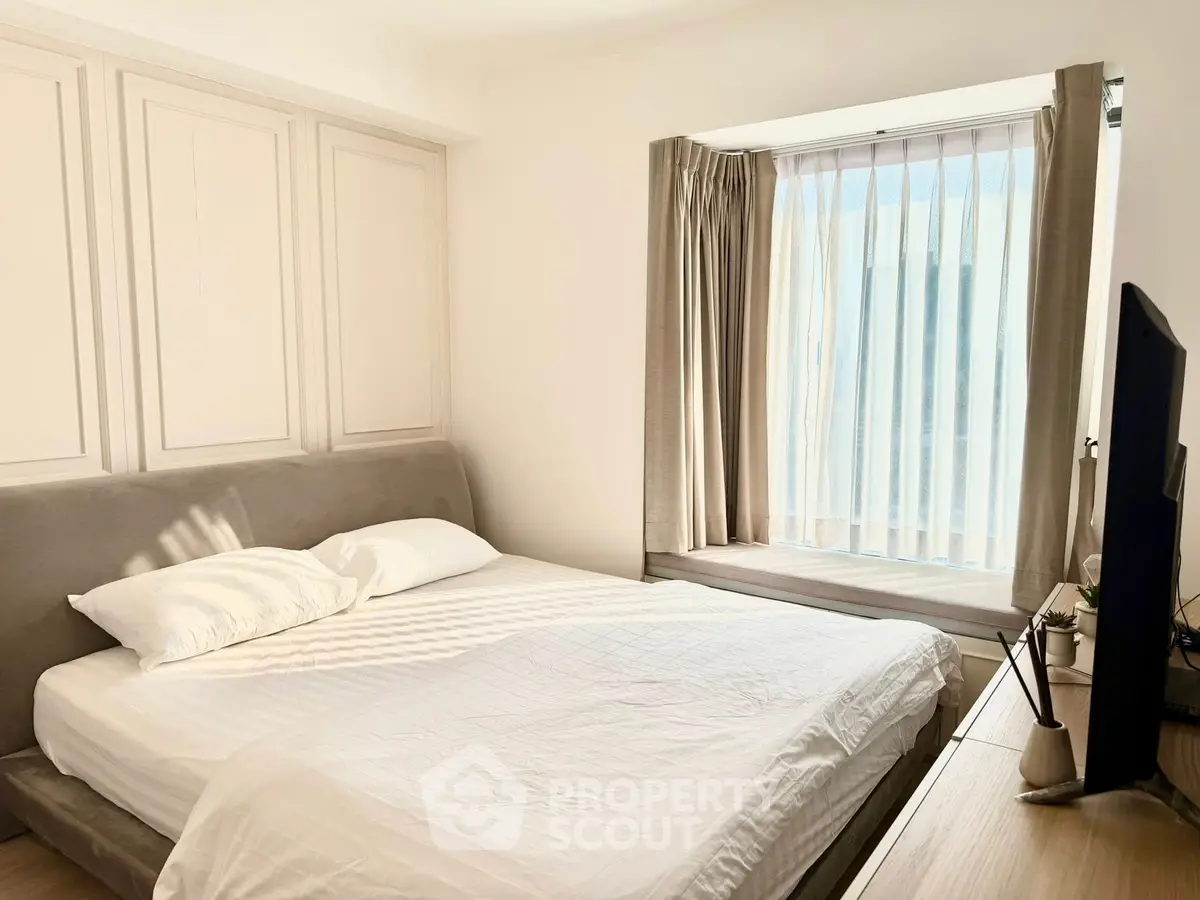 Bright and cozy bedroom with modern decor and large window for natural light.