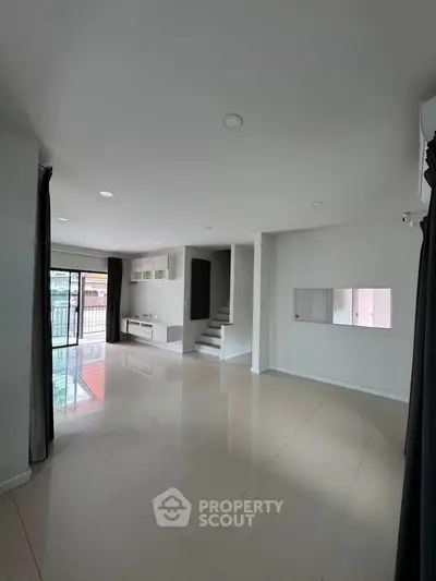 Spacious modern living room with large windows and sleek tile flooring, perfect for family gatherings.