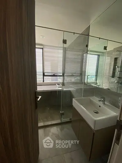 Modern bathroom with glass shower and city view from window.