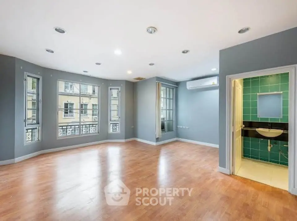 Spacious living room with hardwood floors and adjacent bathroom in modern apartment.