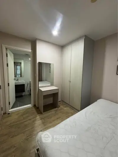 Cozy bedroom with ensuite bathroom and modern wardrobe in stylish apartment.