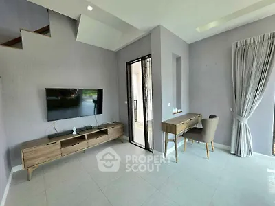 Modern living room with sleek furniture and natural light, featuring a wall-mounted TV and stylish desk area.