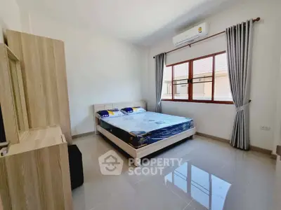 Spacious bedroom with modern furnishings and large window for natural light.