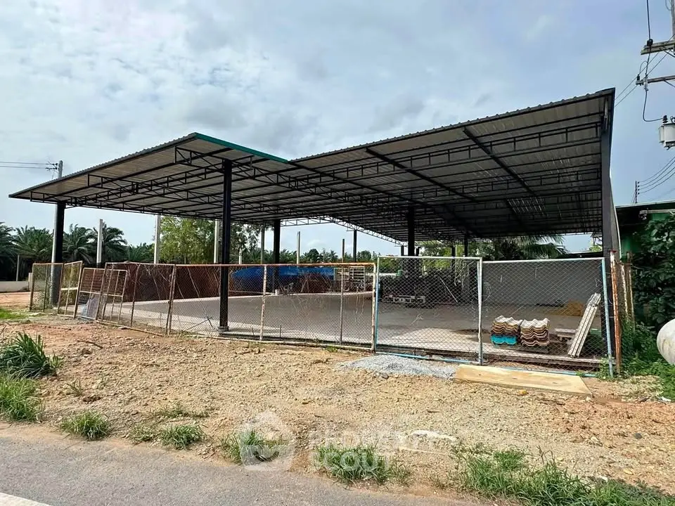 Spacious open-air industrial structure with metal roofing and fenced perimeter, ideal for commercial use.