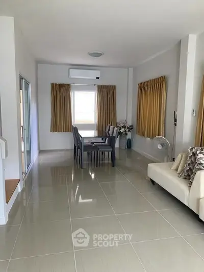 Spacious living room with modern dining area and elegant decor, featuring large windows and stylish furnishings.