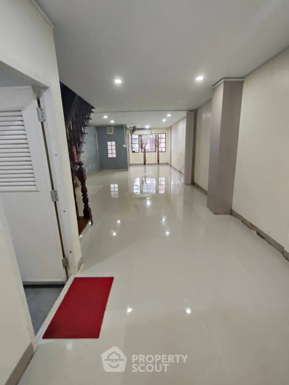 Spacious open-plan living area with glossy tiled floors and staircase, ideal for modern family living.