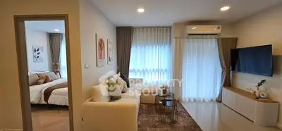 Modern living room with cozy sofa, wall-mounted TV, and view into stylish bedroom.