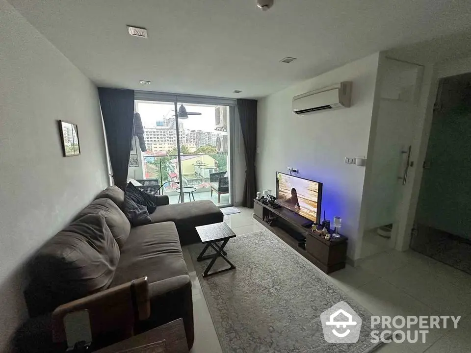 Modern living room with balcony view, featuring cozy sofa and entertainment setup.