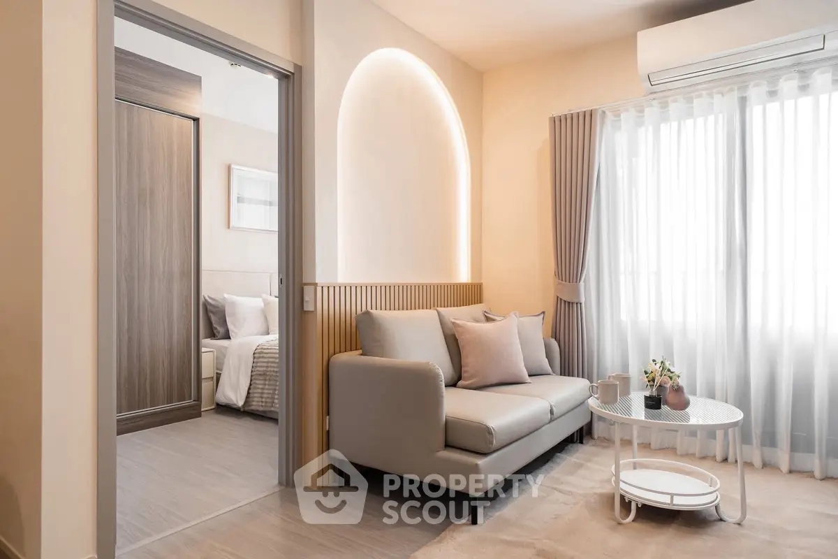 Modern living room with cozy sofa and natural light, adjacent to a stylish bedroom.
