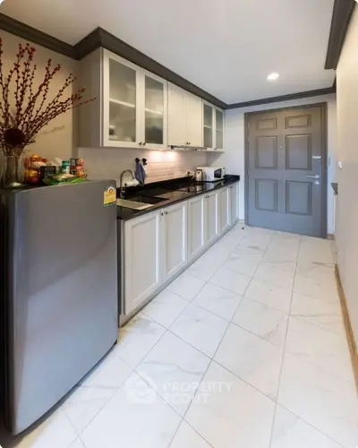 Modern kitchen with sleek cabinetry and stainless steel fridge in a stylish apartment.