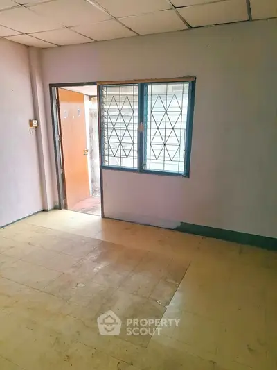 Spacious room with tiled floor and window, ideal for customization in a residential property.