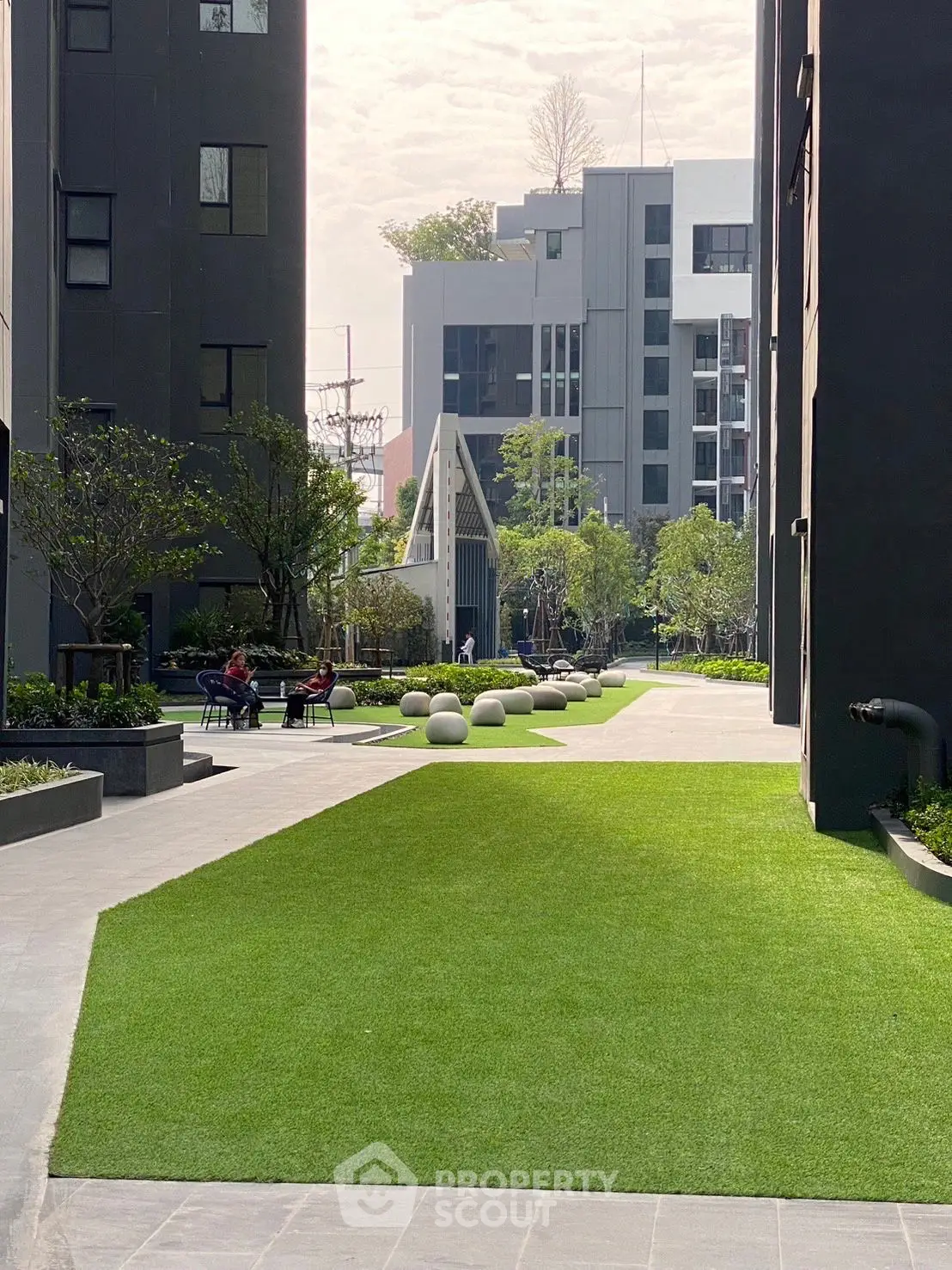 Modern urban garden with lush green lawns and seating area in a residential complex.