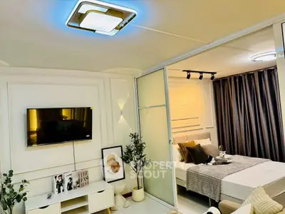 Modern living room with TV and cozy bedroom separated by sliding glass doors.