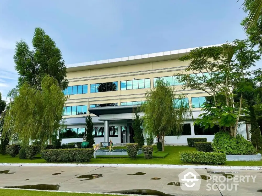 Modern commercial building exterior with lush green landscaping and expansive glass facade offering a professional corporate environment.