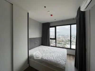 Modern bedroom with city view, featuring large window and minimalist design.