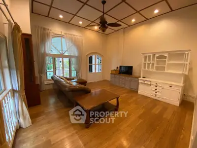 Spacious living room with elegant wooden flooring and classic furniture, featuring large windows for natural light.