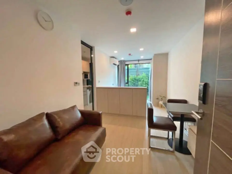 Modern open-plan living room with brown leather sofa and dining area, featuring sleek design and natural light.
