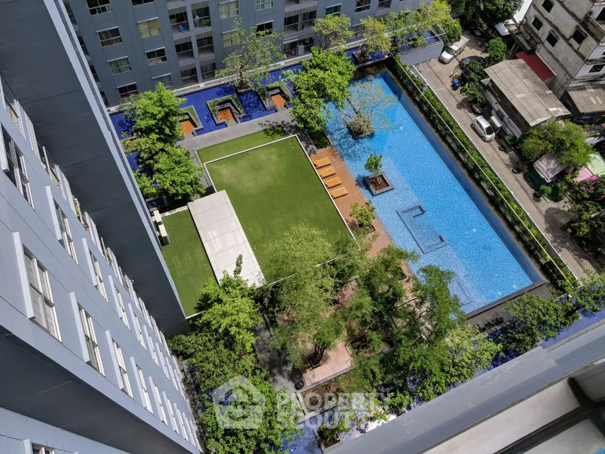 Stunning aerial view of modern residential complex with lush garden and inviting swimming pool.