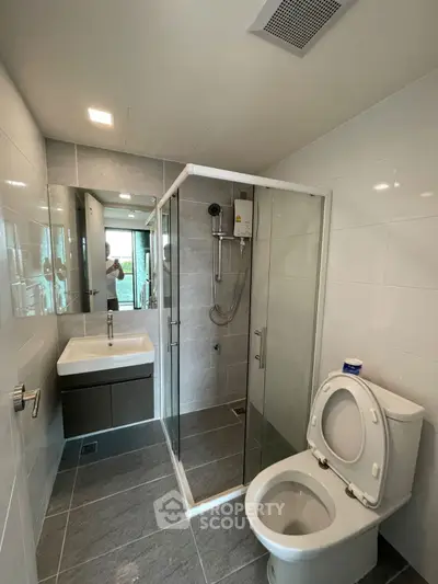 Modern bathroom with glass shower and sleek fixtures in contemporary home.