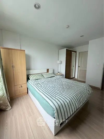 Spacious bedroom with modern decor and ample natural light, featuring a comfortable bed and wooden furniture.
