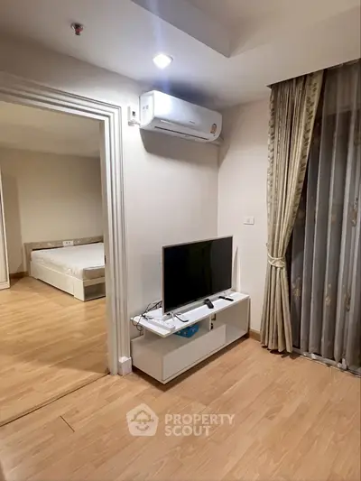 Modern living room with TV, air conditioning, and view into bedroom