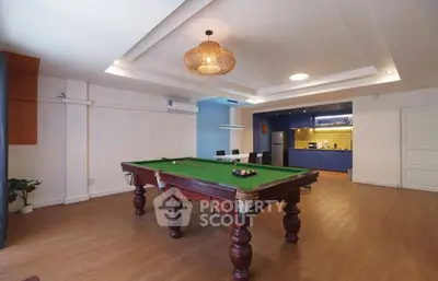 Spacious living room with pool table and modern kitchen in open layout