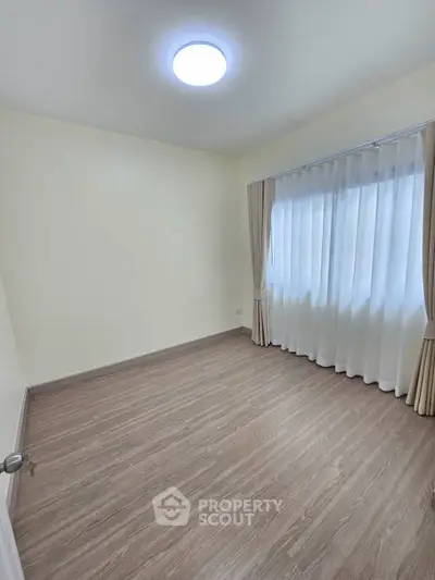 Spacious empty room with elegant curtains and modern flooring, perfect for customization.