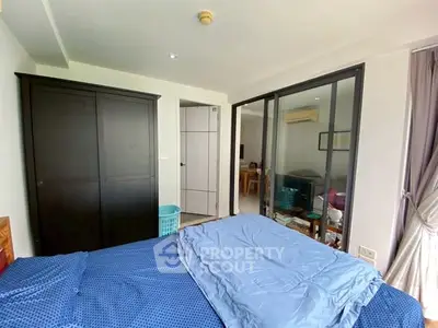 Spacious bedroom with large wardrobe and sliding glass doors leading to a bright living area.