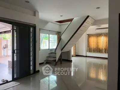 Spacious modern living room with staircase and large windows, perfect for family gatherings.