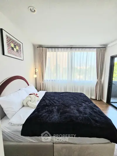 Cozy bedroom with large window and elegant decor, perfect for relaxation.