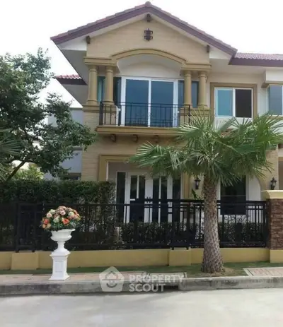 Elegant two-story house with balcony and lush landscaping