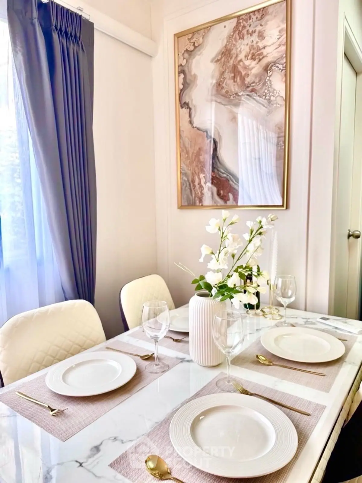 Elegant dining area with marble table, chic decor, and natural light.