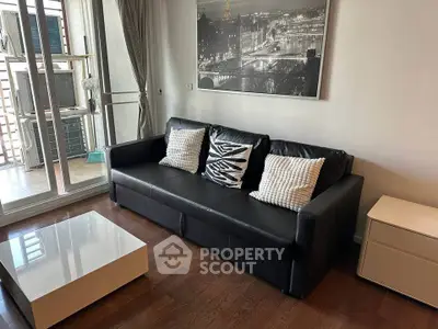 Modern living room with sleek black sofa, stylish decor, and balcony access in a chic apartment.