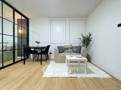 Modern living room with elegant decor and cozy seating area, featuring a stylish dining nook and sleek glass partition.