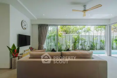 Modern living room with large windows overlooking lush garden and pool